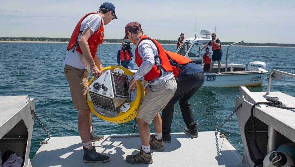 学生 on a boat preparing a white shark buoy for deployment